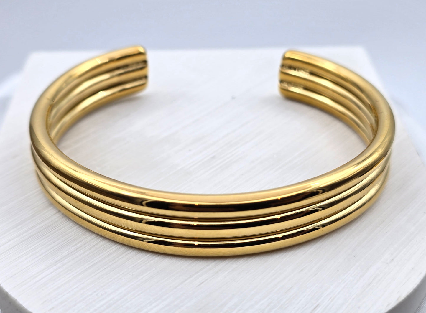 *BRAZALETE RIGIDO TRES LINEAS TUBULARES; TONO DORADO*