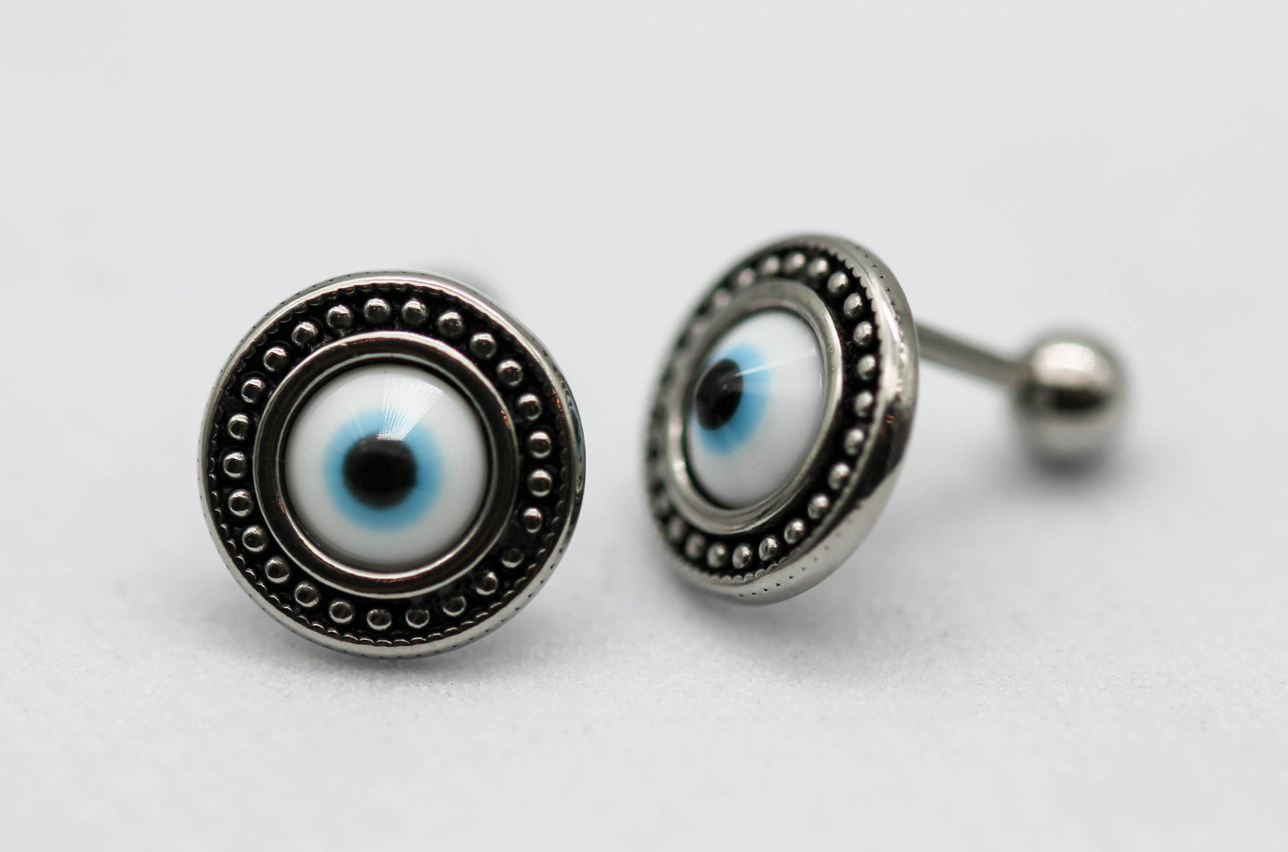 BROQUELES OJO AZUL CON TOPE DE ROSCA; TONO PLATEADO