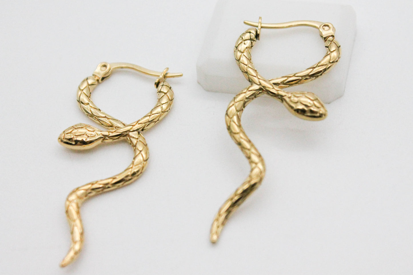 ARETES LARGOS SERPIENTE CRUZADA CON TEXTURA, TONO DORADO