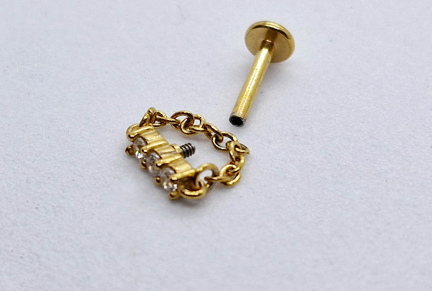 PIERCING TRES CIRCONIAS EN LINEA Y CADENA; TONO DORADO