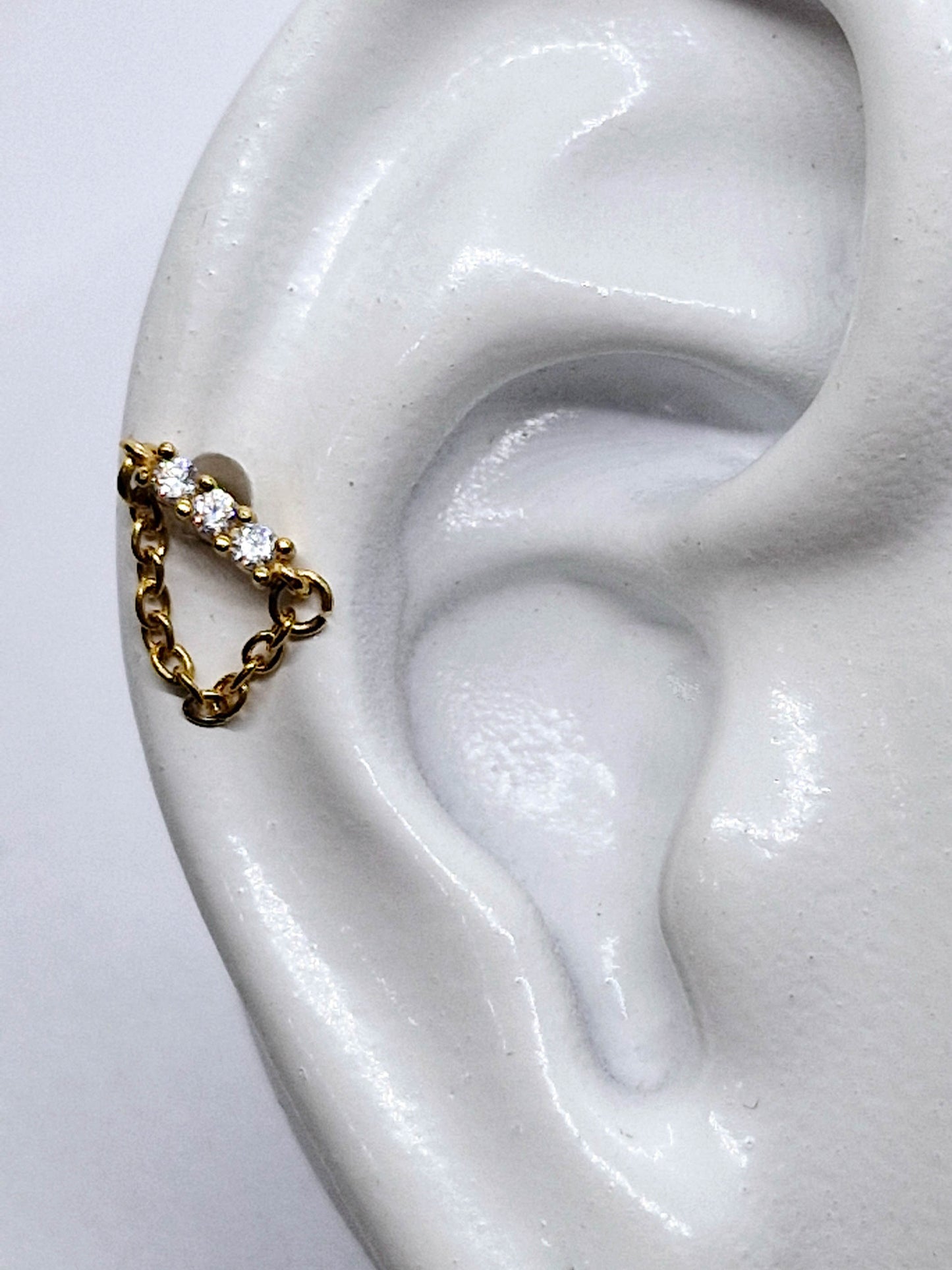 PIERCING TRES CIRCONIAS EN LINEA Y CADENA; TONO DORADO