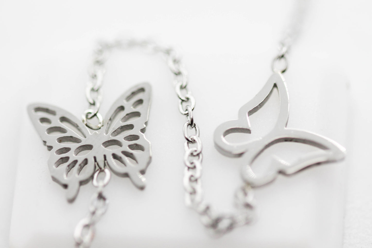 COLLAR 2 MARIPOSAS HUECAS, 2 GRABADAS, CIRCONIA 6MM AL CENTRO FLOR 9MM COLGANDO,40CM + EXTENSION 5CM; TONO PLATEADO