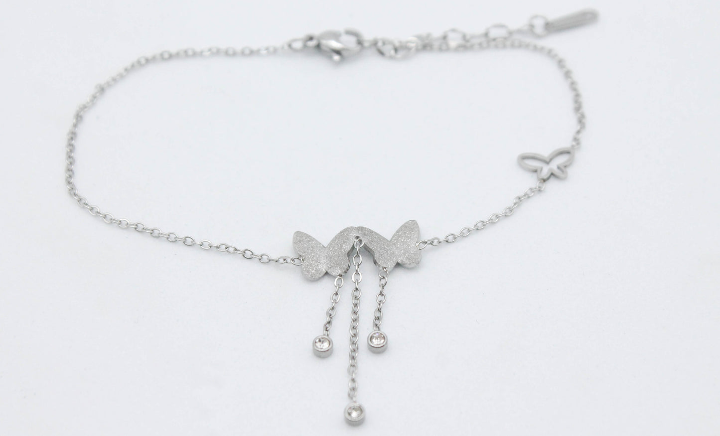TOBILLERA 2 MARIPOSAS AZUCARADAS (8MM) 3 CIRCONIAS COLGANDO(3MM) 21CM + 4CM DE EXTENSION; TONO PLATEADO
