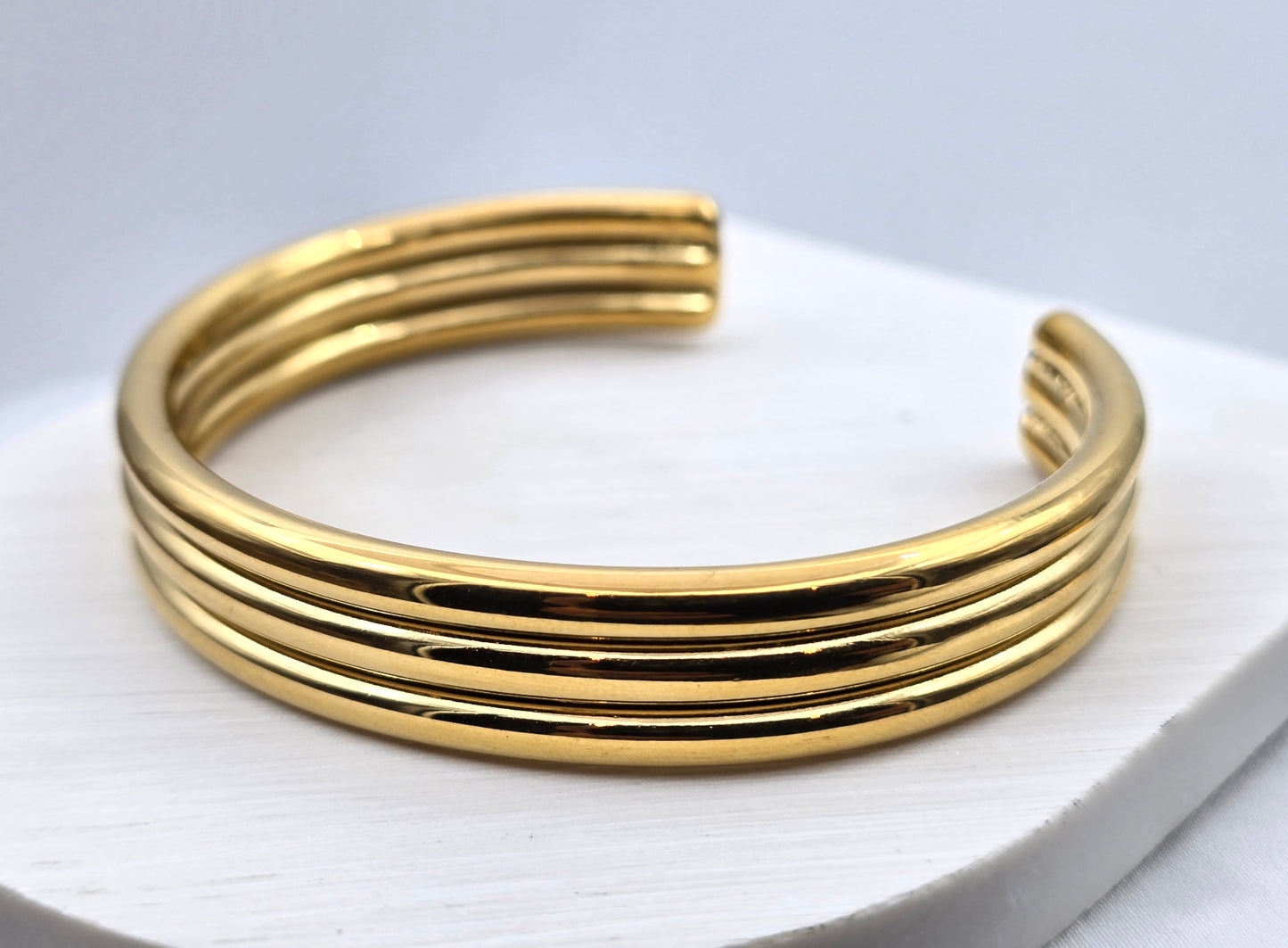 *BRAZALETE RIGIDO TRES LINEAS TUBULARES; TONO DORADO*