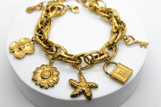 PULSERA DIJES COLGANTES FLOR, GIRASOL, ESTRELLA DE MAR, CANDADO, LLAVE; TONO DORADO