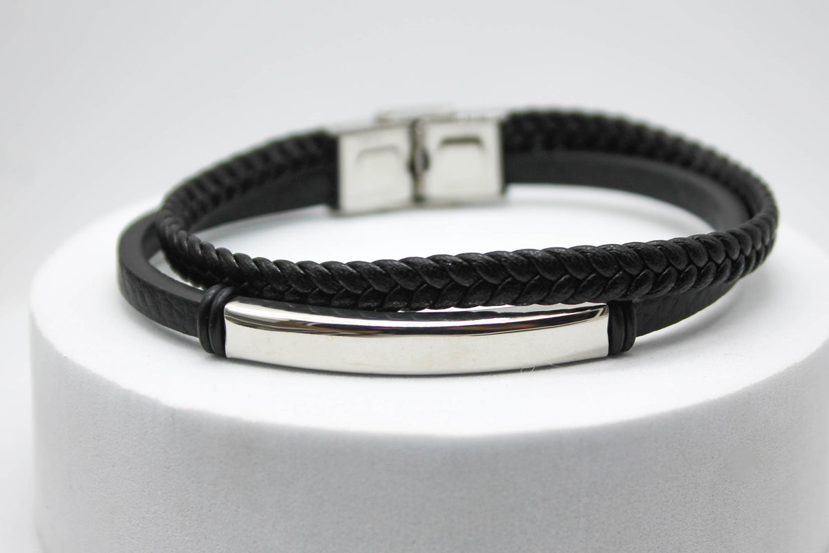 PULSERA CABALLERO PIEL NEGRA DOBLE PLANA Y TRENZADA PLACA ACERO; TONO PLATEADO