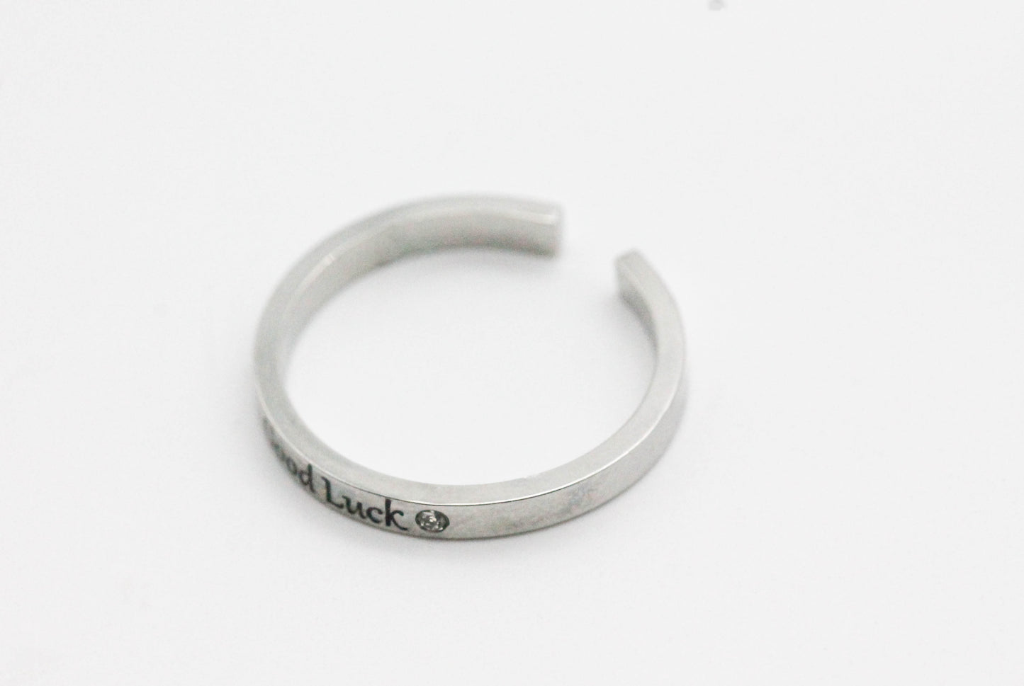 ANILLO AJUSTABLE SOLITARIO "GOOD LUCK", TONO PLATEADO