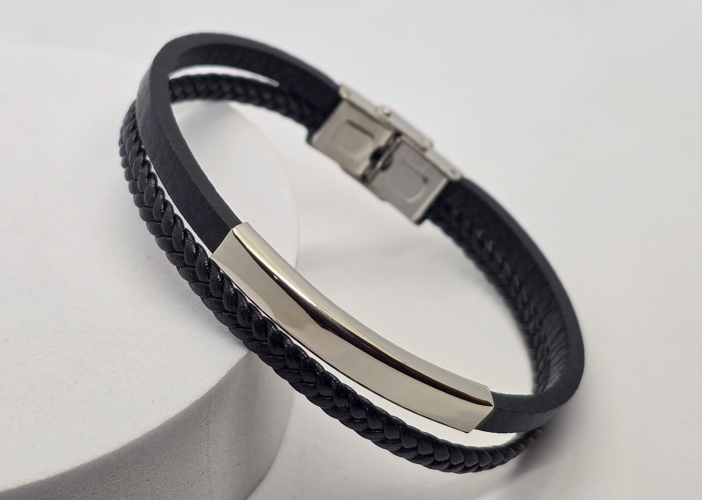 PULSERA CABALLERO PIEL NEGRA DOBLE PLANA Y TRENZADA PLACA ACERO; TONO PLATEADO